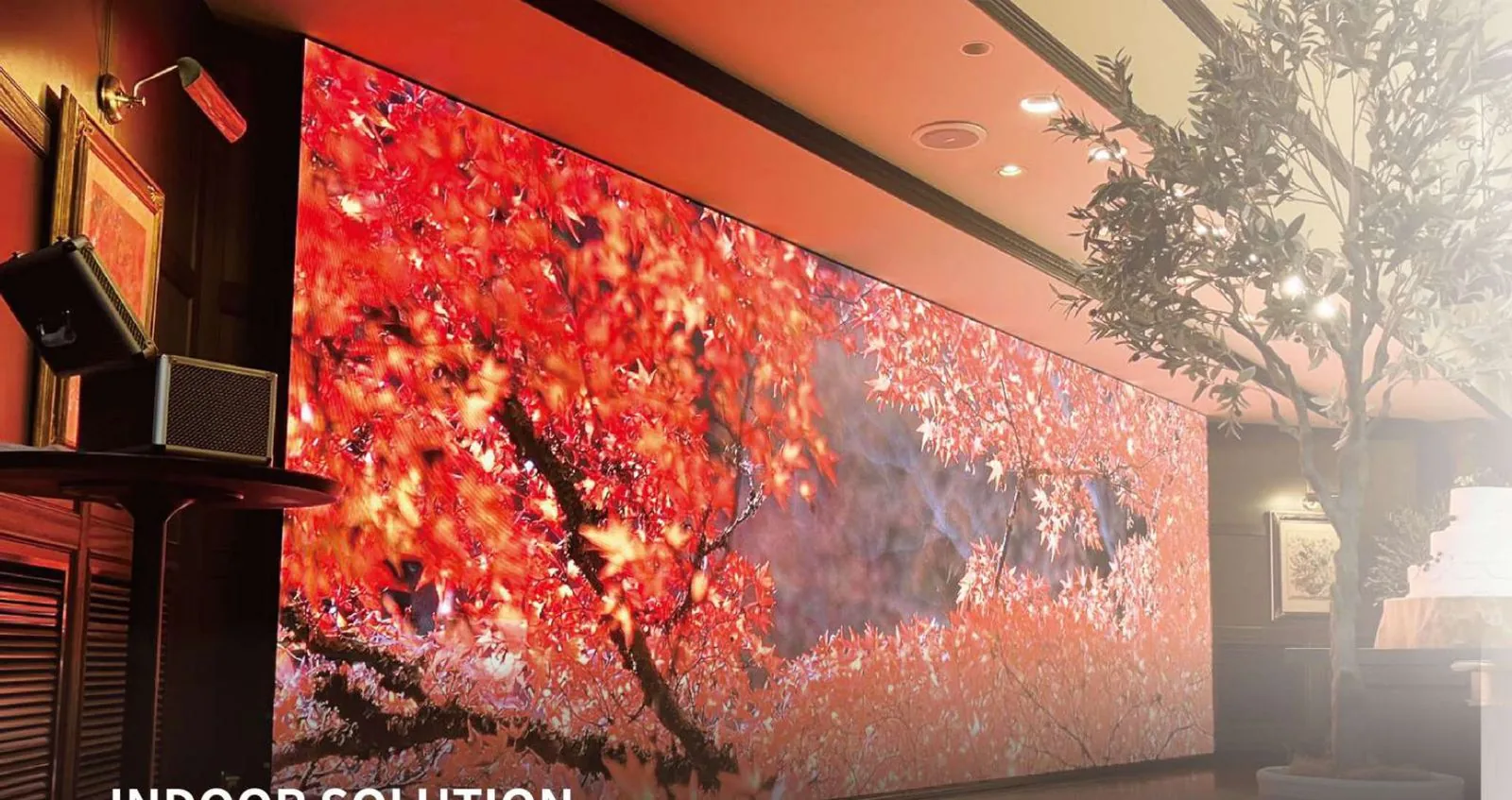 Large indoor LED wall showing red tree visuals in a venue